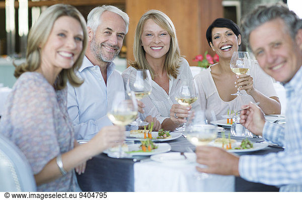 Portrait of smiling people toasting with white wine in restaurant