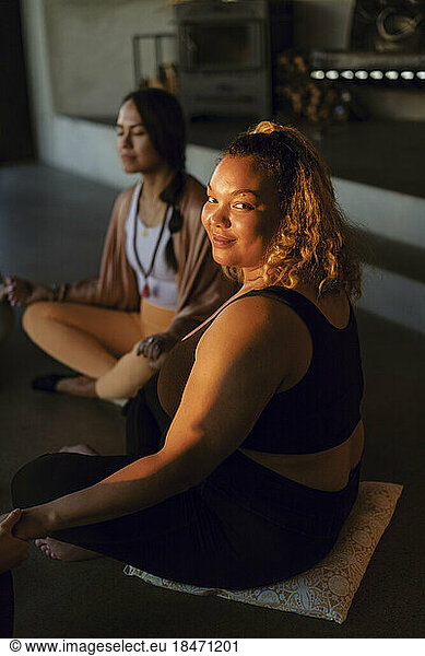 Portrait of smiling plus size woman sitting with female friend at retreat center