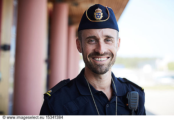 Portrait of smiling policeman standing outside police station