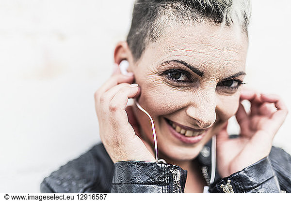 Portrait of smiling punk woman listening to music with earbuds