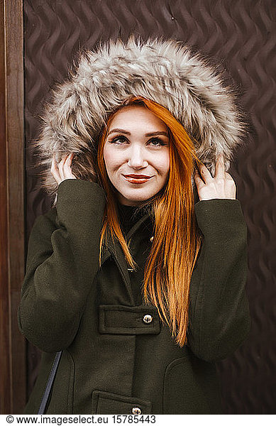 Portrait of smiling redheaded young woman wearing hooded jacket