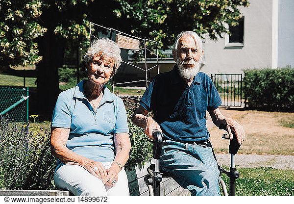 Portrait of smiling retired senior man and woman sitting at back yard
