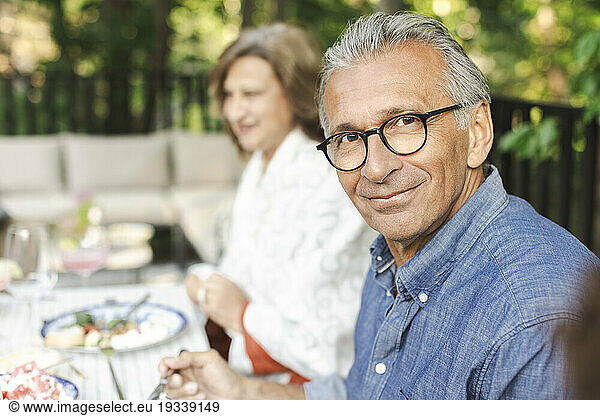 Portrait of smiling retired senior man sitting at dining table