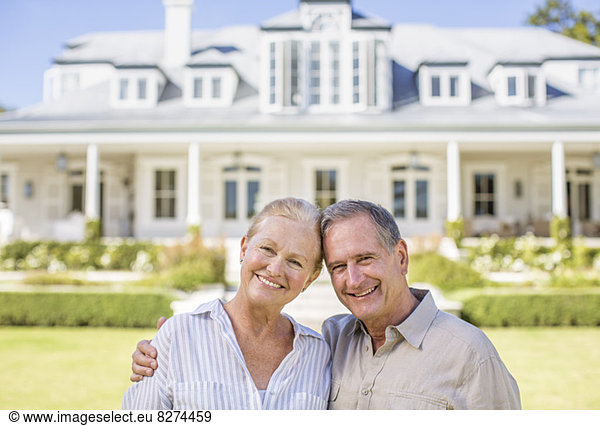 Portrait of smiling senior couple in front of house