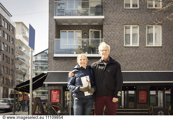 Portrait of smiling senior couple standing against building
