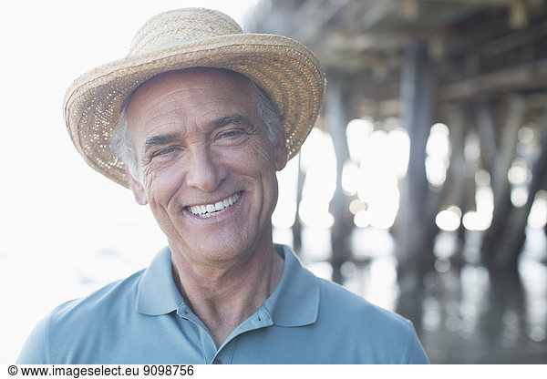 Portrait of smiling senior man in sun hat at beach