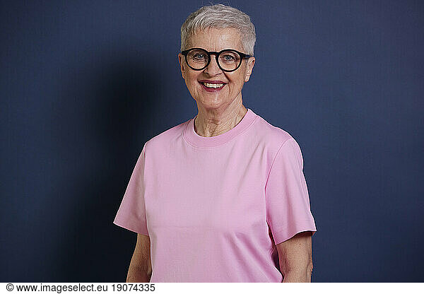 Portrait of smiling senior woman against blue background