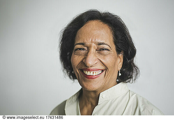 Portrait of smiling senior woman against wall