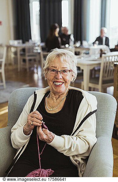 Portrait of smiling senior woman knitting in nursing home