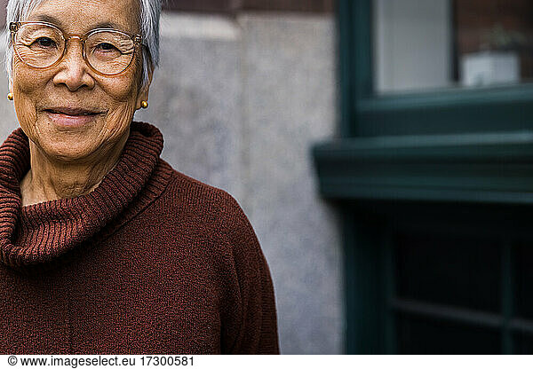 Portrait of smiling senior woman wearing glasses in the city
