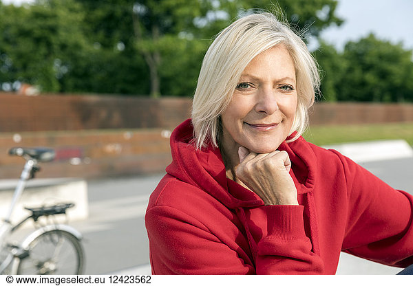Portrait of smiling senior woman wearing red hoodie outdoors