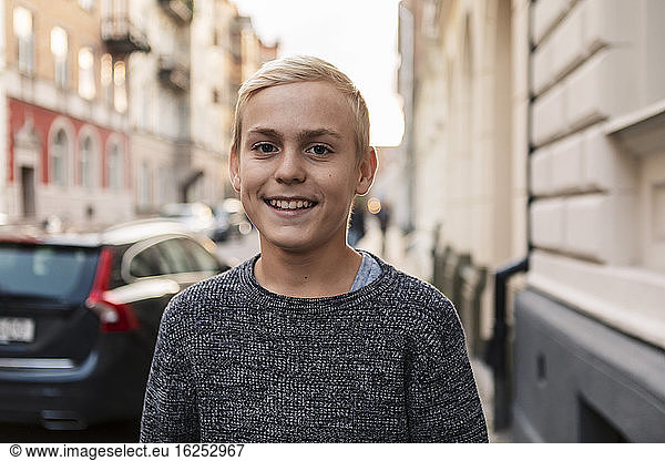 Portrait of smiling teenage boy in city during weekend