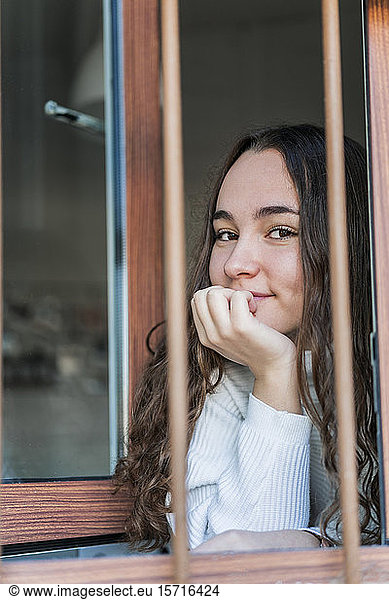 Portrait of smiling teenage girl looking out of window