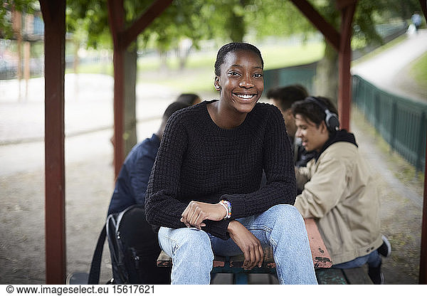 Portrait of smiling teenage girl sitting at park