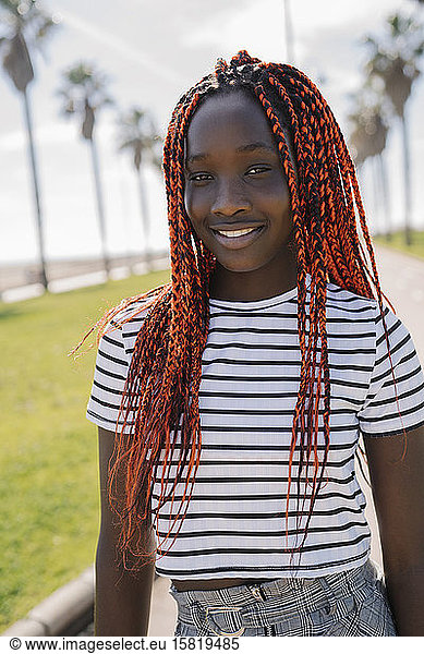 Portrait of smiling teenage girl with braids outdoors