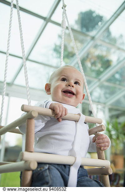 Portrait of smiling toddler sitting in a swing