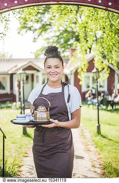 Portrait of smiling waitress holding serving tray at restaurant