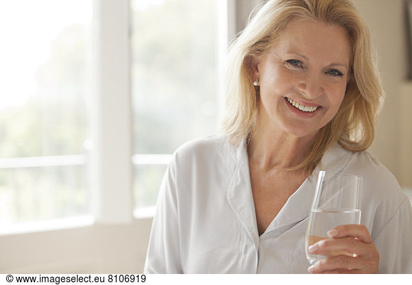 Portrait of smiling woman drinking glass of water