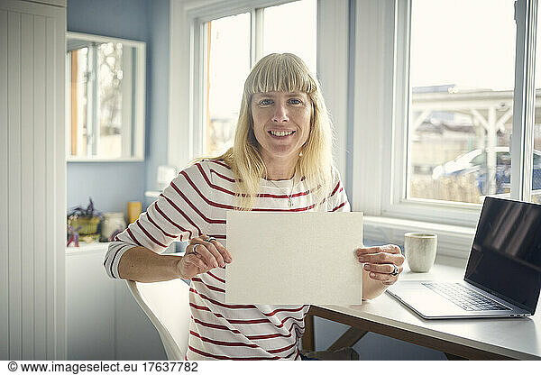 Portrait of smiling woman holding blank paper