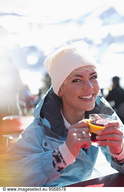 Portrait of smiling woman in warm clothing drinking tea
