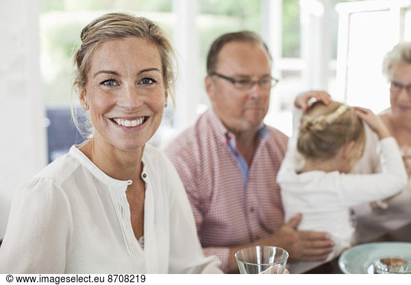 Portrait of smiling woman sitting at dining table with family