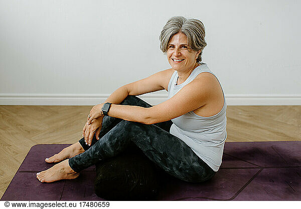 Portrait of smiling woman sitting on exercise mat