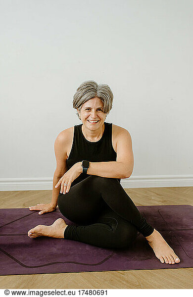 Portrait of smiling woman sitting on exercise mat