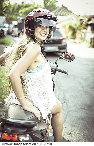 Portrait of smiling woman sitting on motor scooter