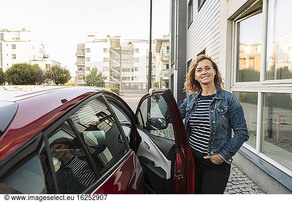 Portrait of smiling woman standing by car