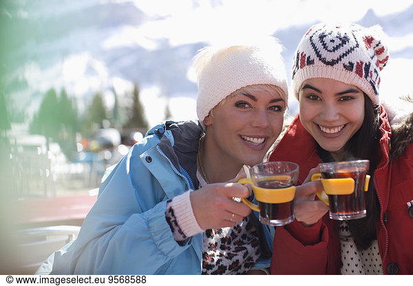 Portrait of smiling women in warm clothing drinking tea outdoors
