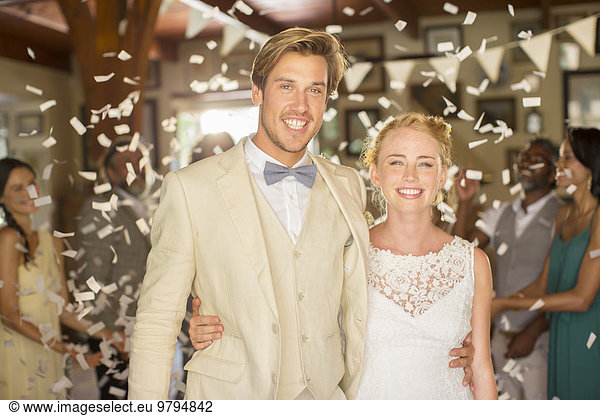 Portrait of smiling young couple standing in falling confetti during wedding reception