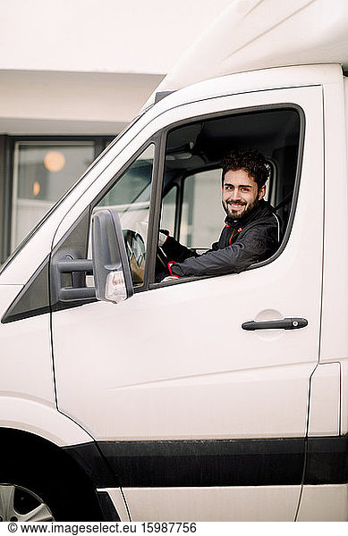 Portrait of smiling young delivery man driving truck
