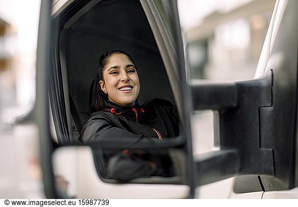 Portrait of smiling young delivery woman driving truck