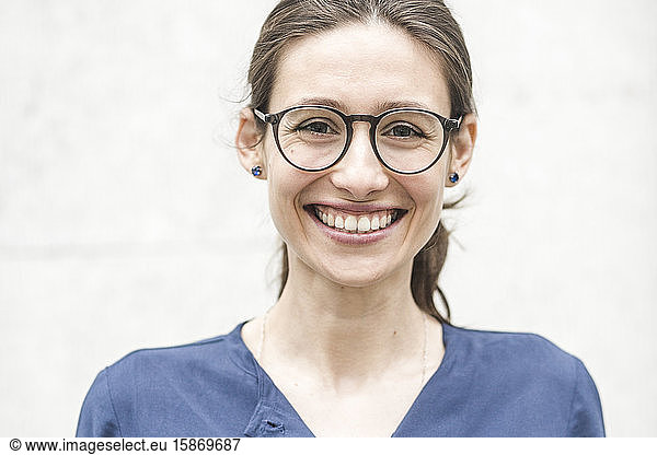 Portrait of smiling young entrepreneur against wall