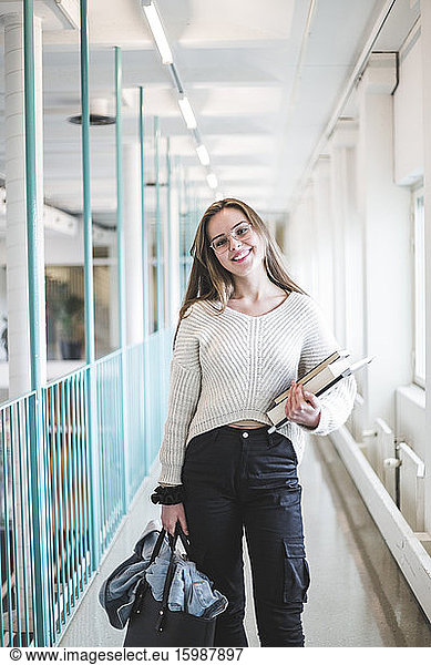Portrait of smiling young female student in corridor of university