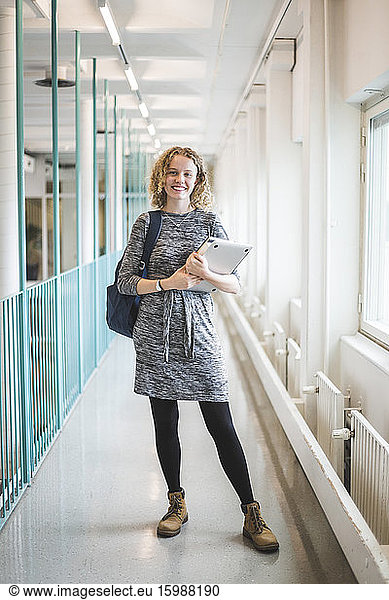 Portrait of smiling young female student in corridor of university