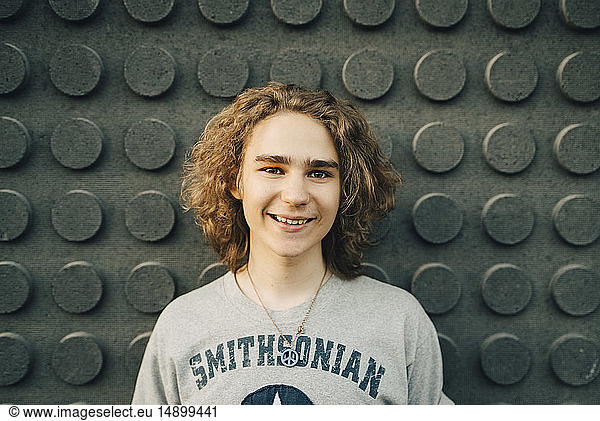 Portrait of smiling young man standing against wall