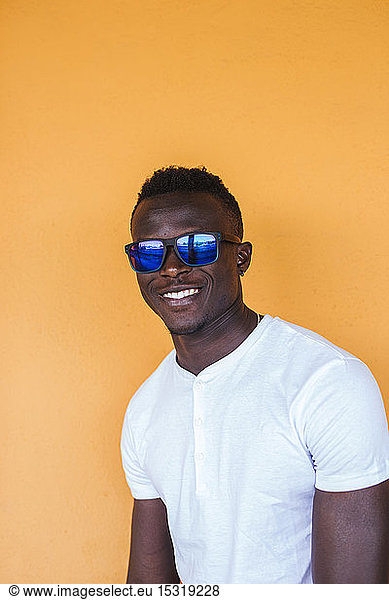 Portrait of smiling young man wearing white t-shirt and sunglasses