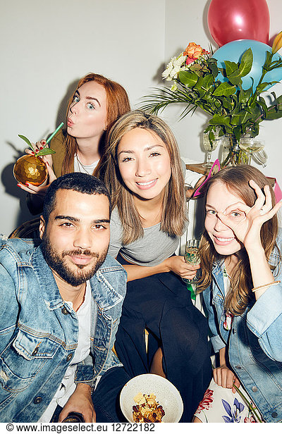 Portrait of smiling young multi-ethnic friends enjoying dinner party at apartment
