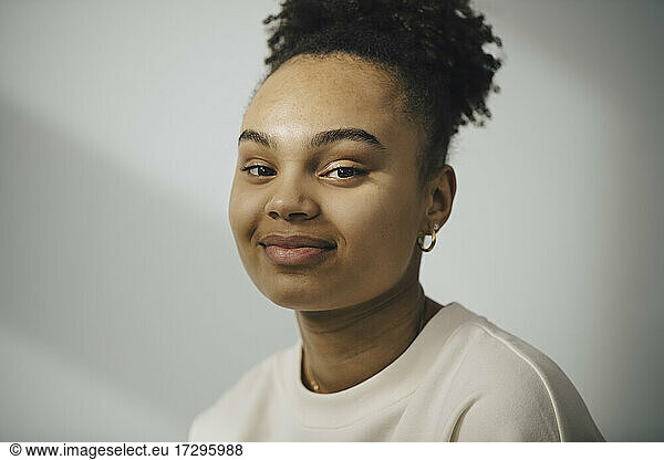 Portrait of smiling young woman against white wall