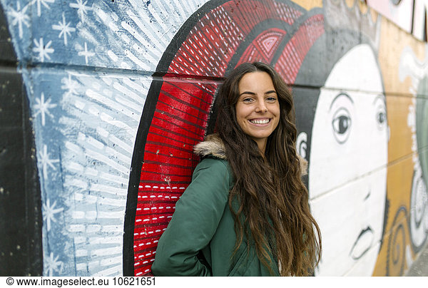 Portrait of smiling young woman at mural