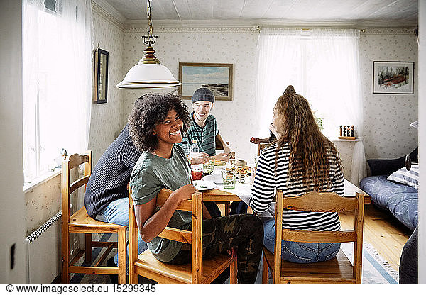 Portrait of smiling young woman enjoying social gathering with friends at home