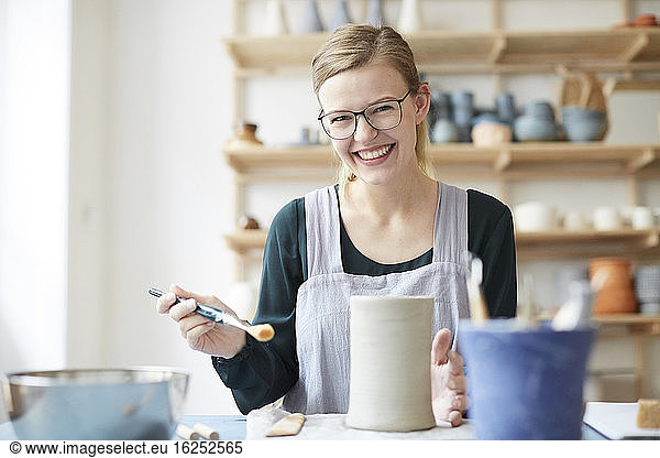 Portrait of smiling young woman learning pottery in art studio