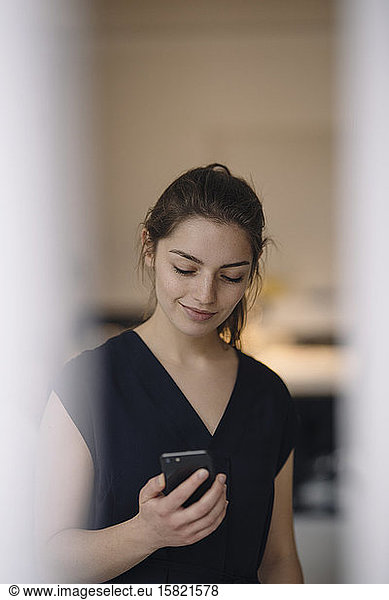 Portrait of smiling young woman looking at mobile phone