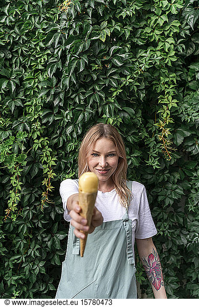 Portrait of smiling young woman offering ice cream cone