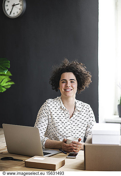 Portrait of smiling young woman sitting at desk in office