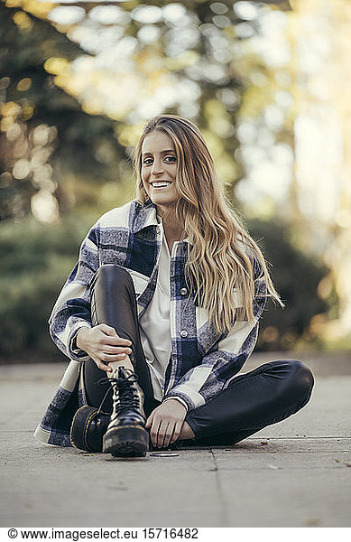 Portrait of smiling young woman sitting on the ground outdoors