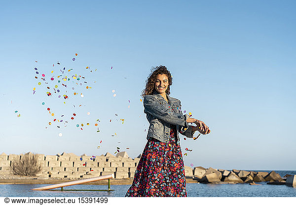 Portrait of smiling young woman throwing confetti in the air