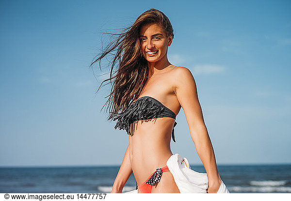 Portrait of smiling young woman wearing bikini on the beach