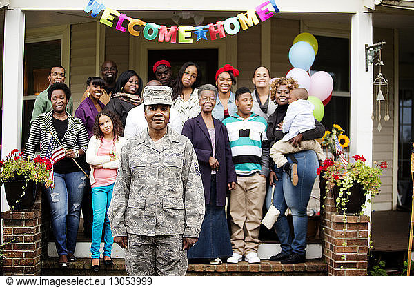 Portrait of soldier standing against family outside house